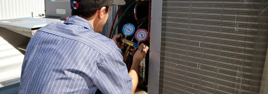 HVAC technician servicing a condenser unit in Bayville